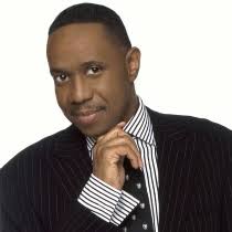 Freddie Jackson in a pinstriped suit and striped shirt, resting his chin on his hand.