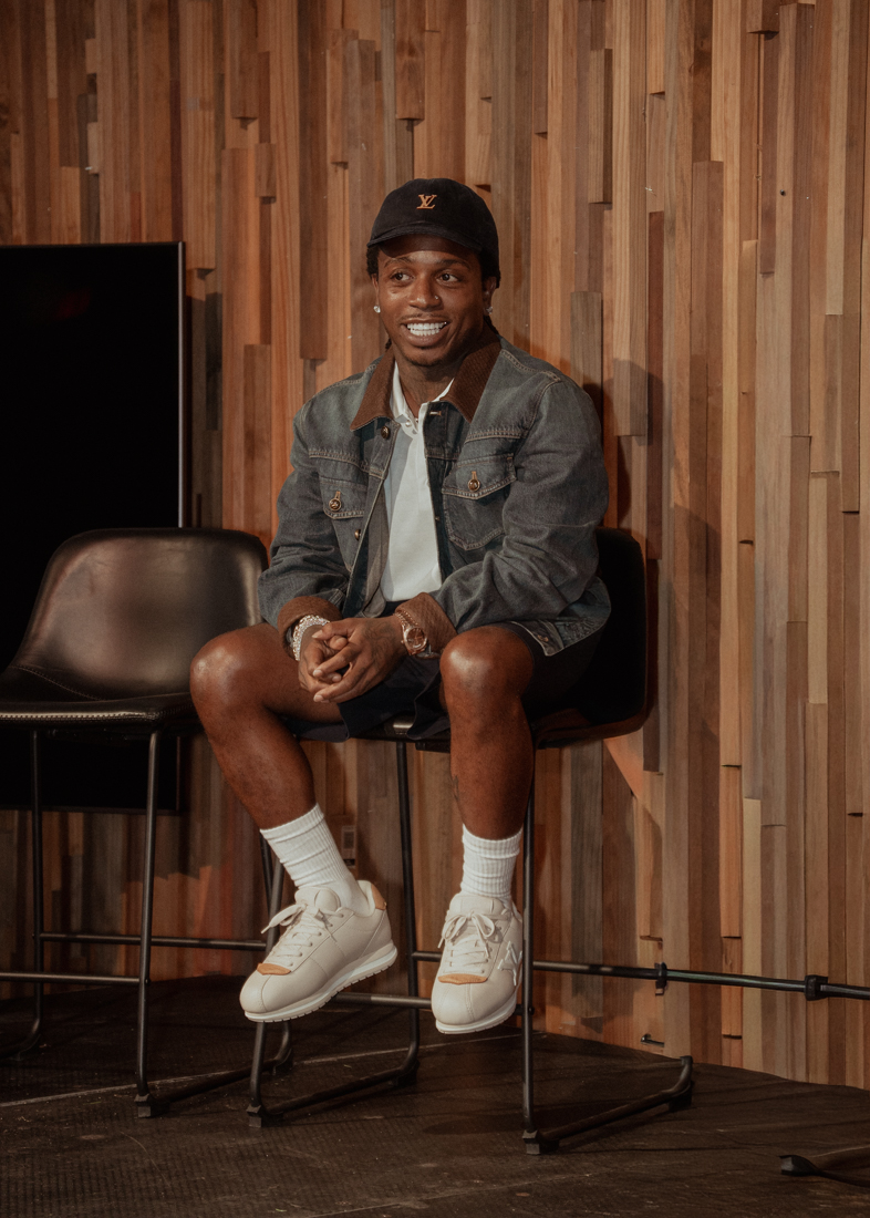 Jacquees seated on a stool on stage during the Cover Conversations event in Atlanta.