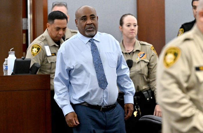 Duane &ldquo;Keffe D&rdquo; Davis stands in a Las Vegas courtroom in a light blue shirt and patterned tie, flanked by Clark County corrections officers.
