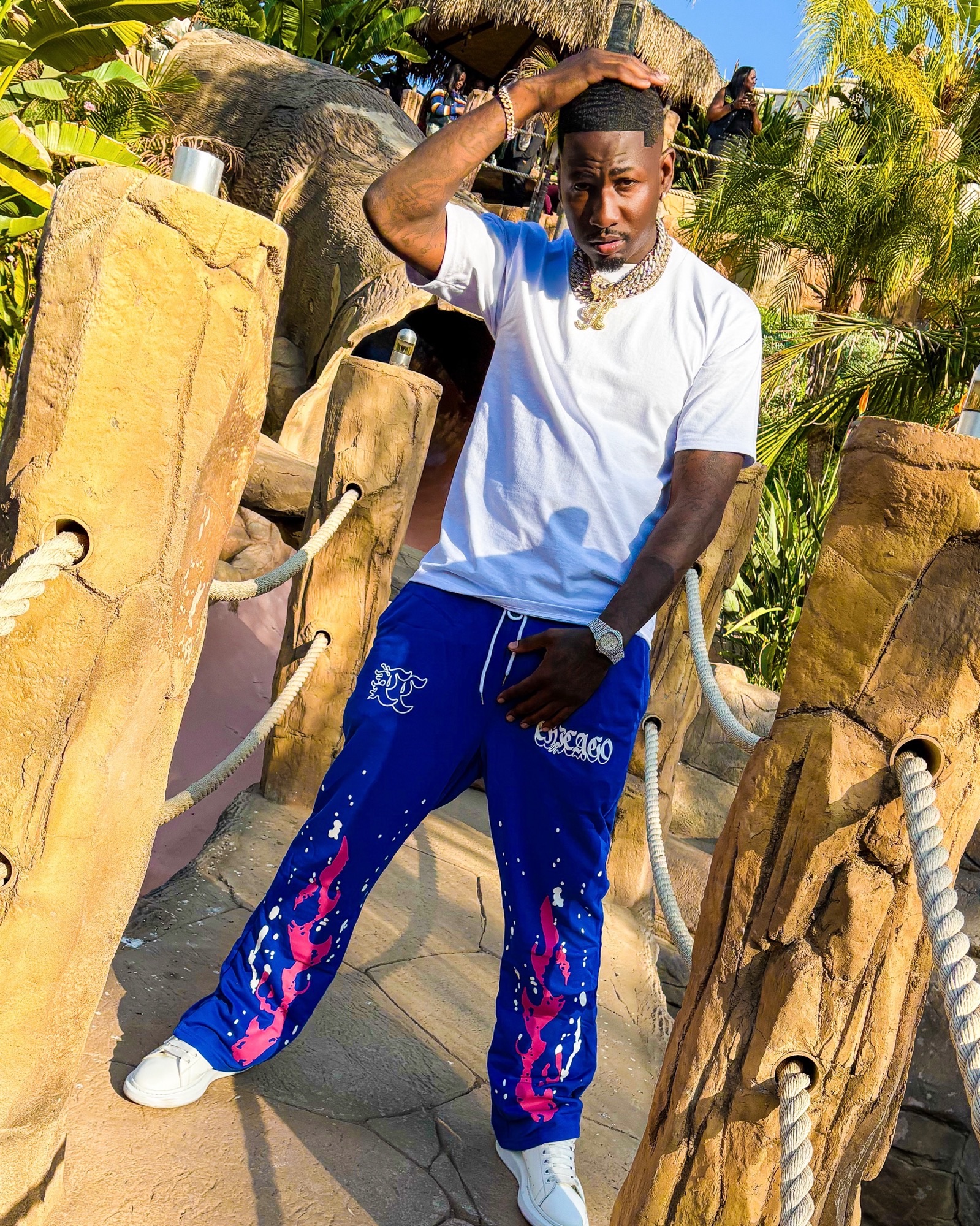 Krizko in a white tee and royal blue Chicago-print sweatpants with iced chains and a diamond watch.