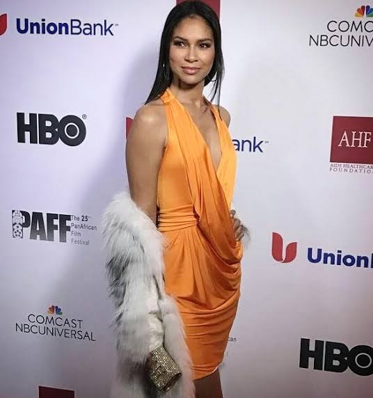 Shireen Crutchfield on a red carpet in an orange gown.